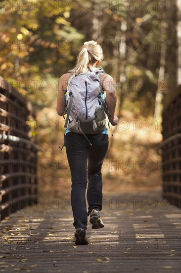 USA, Utah, young woman jogging on footbridge. Photo : Mike Kemp