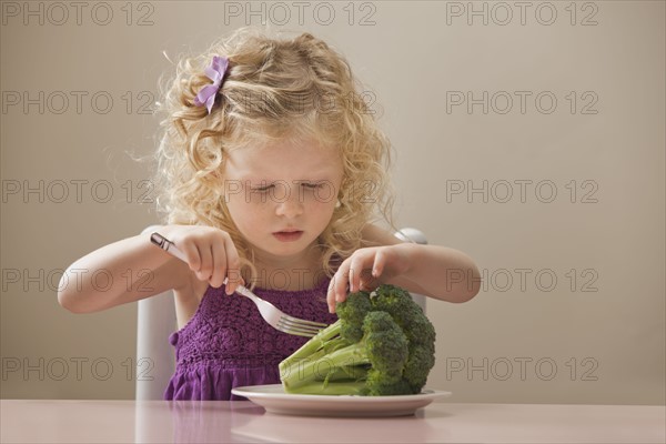 USA, Utah, Lehi, girl (2-3) eating broccoli. Photo : Mike Kemp