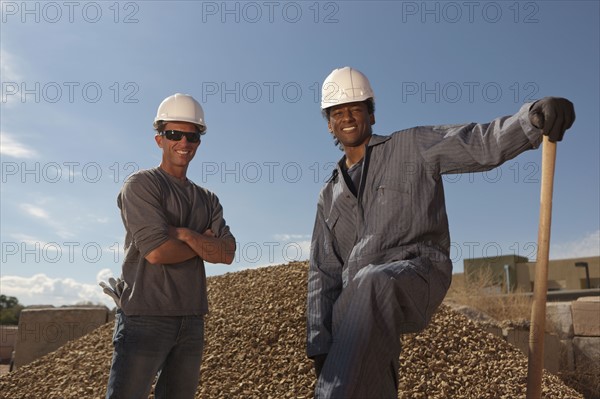 Portrait of two construction workers by rubble on building site. Photo : Dan Bannister