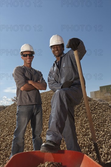 Portrait of two construction workers by rubble on building site. Photo : Dan Bannister