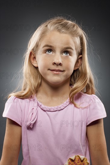 Portrait of girl (8-9) looking up, studio shot. Photo : FBP