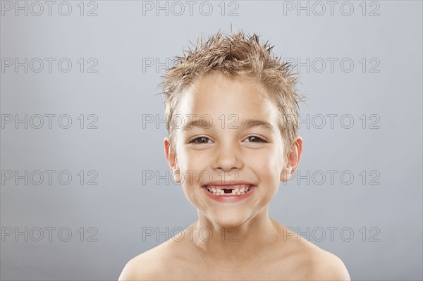 Studio portrait of toothless boy (8-9) smiling. Photo : FBP