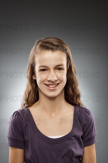 Portrait of girl (12-13) looking at camera and smiling, studio shot. Photo : FBP