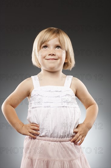 Girl (2-3) with hands on hip and looking up, studio shot. Photo : FBP