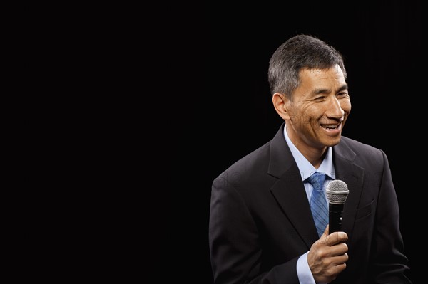 USA, Utah, Provo, Smiling businessman with microphone standing ion stage. Photo : FBP