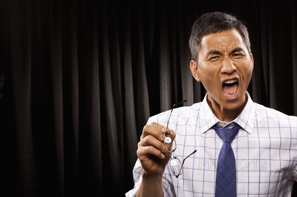 USA, Utah, Provo, Portrait of businessman standing in front of black curtain. Photo : FBP