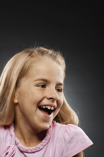 Portrait of laughing girl (8-9) looking away, studio shot. Photo : FBP