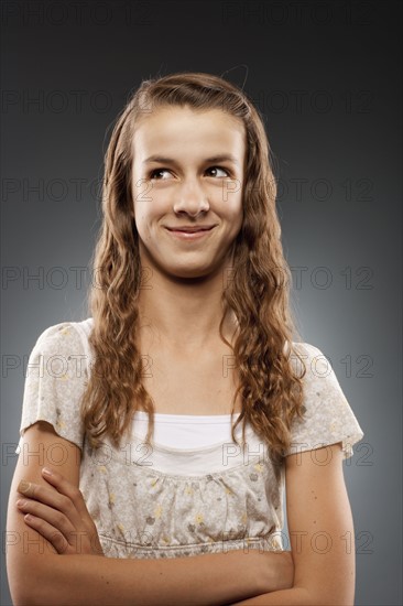 Portrait of girl (12-13) looking at camera with arms crossed, studio shot. Photo : FBP