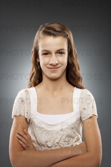 Portrait of girl (12-13) looking at camera with arms crossed, studio shot. Photo : FBP