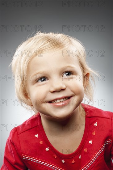 Portrait of happy girl (2-3) looking up, studio shot. Photo : FBP