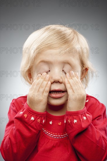 Portrait of girl (2-3) with hands covering eyes, studio shot. Photo : FBP