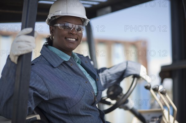 Portrait of female construction worker driving mechanical digger. Photo : Dan Bannister