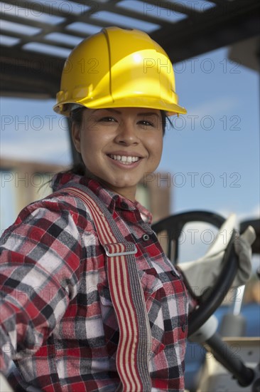 Portrait of female construction worker driving mechanical digger. Photo : Dan Bannister