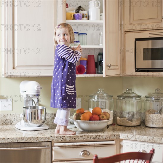 USA, Utah, Girl (2-3) climbing on cupboard in kitchen. Photo : Tim Pannell