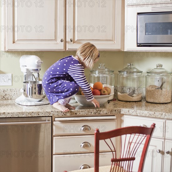 USA, Utah, Girl (2-3) climbing on cupboard in kitchen. Photo : Tim Pannell