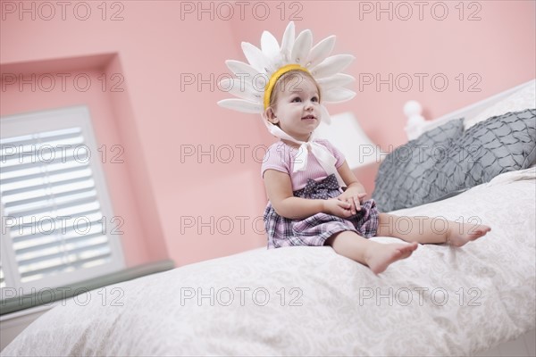 USA, Utah, small girl (2-3) with plume sitting on bed. Photo : Tim Pannell