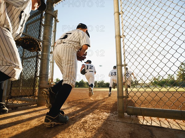 Baseball players (10-11) entering baseball diamond.