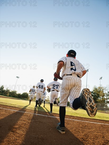 Baseball players (10-11) running on baseball diamond.