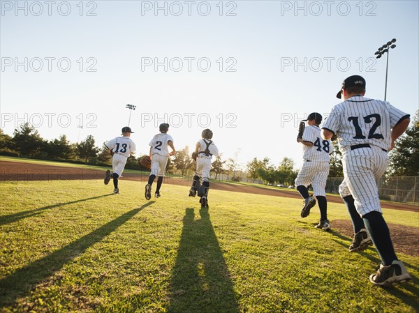 Baseball players (10-11) running on baseball diamond.