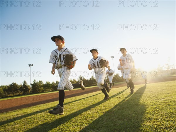 Baseball players (10-11) running on baseball diamond.