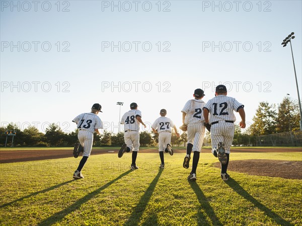 Baseball players (10-11) running on baseball diamond.