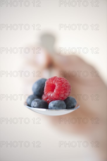 Blueberries and raspberry on spoon.