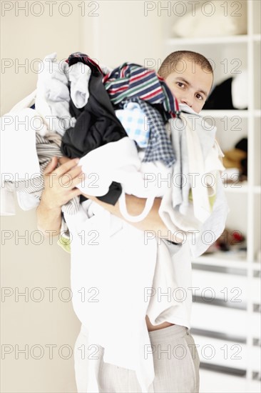 South Africa, Man standing with pile of laundry. Photo : momentimages