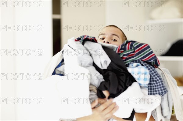 South Africa, Man standing with pile of laundry. Photo : momentimages