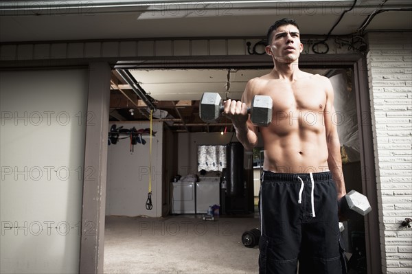 USA, Seattle, Muscular man training with dumbbells. Photo : Take A Pix Media