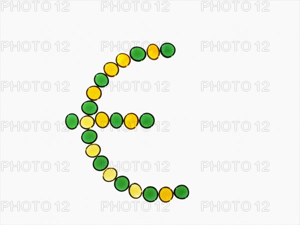 Studio shot of yellow and green glass beads in euro symbol shape. Photo : David Arky