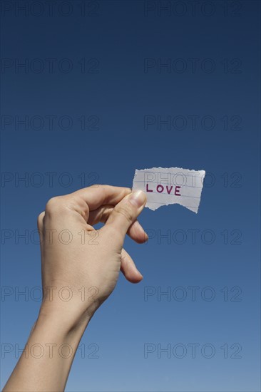 USA, Arizona, Winslow, Human hand holding love note against blue sky. Photo : David Engelhardt