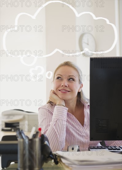 USA, New Jersey, Jersey City, Young attractive businesswoman daydreaming in office. Photo : Jamie Grill Photography