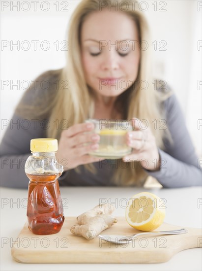 USA, New Jersey, Jersey City, Young woman drinking tea with ginger and lemon. Photo : Jamie Grill Photography