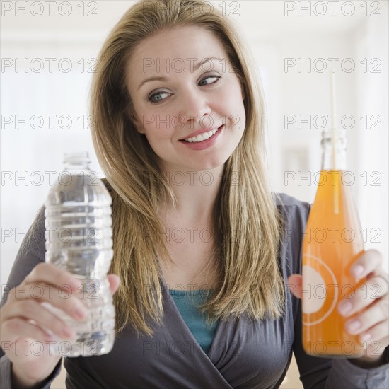 USA, New Jersey, Jersey City, Young woman trying to choose between organic juice and mineral water. Photo : Jamie Grill Photography