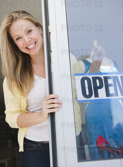 USA, New Jersey, Jersey City, Attractive young woman emerging from shop door. Photo : Jamie Grill Photography