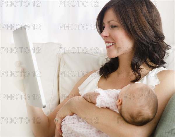 USA, New Jersey, Jersey City, Mother holding baby daughter (2-5 months), reading letter. Photo : Jamie Grill Photography