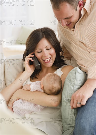 USA, New Jersey, Jersey City, Father watching baby daughter (2-5 months) as mother is using telephone. Photo : Jamie Grill Photography