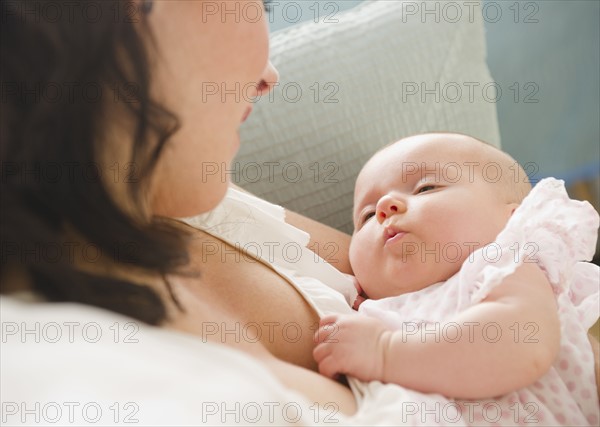 USA, New Jersey, Jersey City, Mother holding baby daughter (2-5 months), reading letter. Photo : Jamie Grill Photography
