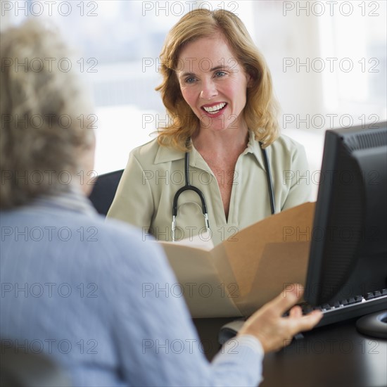 USA, New Jersey, Jersey City, Female doctor discussing medical record with patient in office.