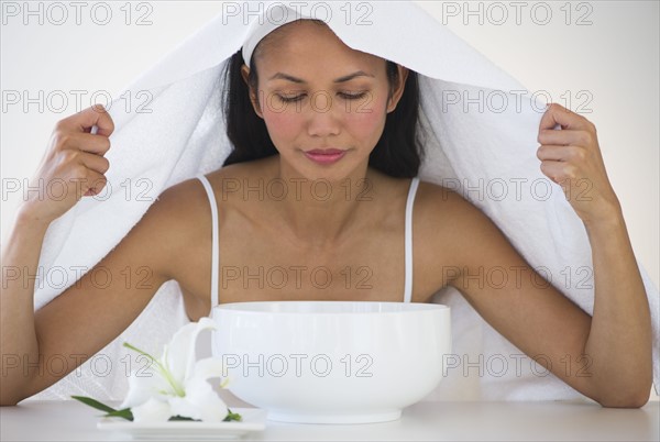 Woman under towel having steam beauty treatment.