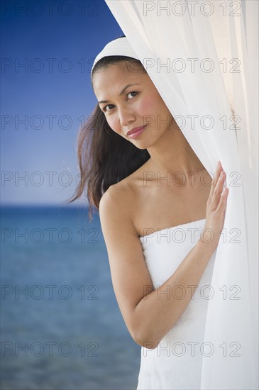 USA, New Jersey, Jersey City, Portrait of woman peering around curtain near sea.