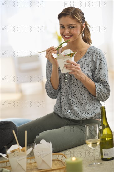 USA, New Jersey, Jersey City, Portrait of young woman eating takeaway food on floor.