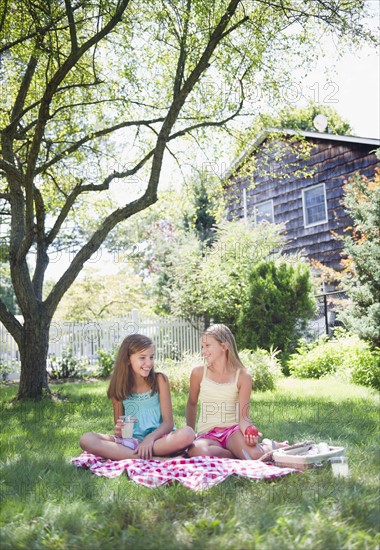 USA, New York, Two girls (10-11, 10-11) sitting on blanket in backyard. Photo : Jamie Grill Photography