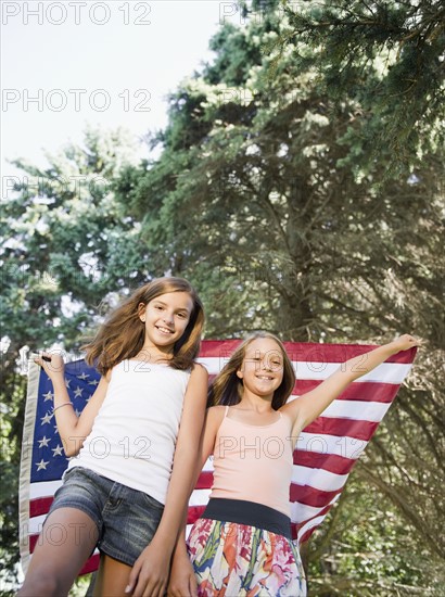 USA, New York, Two girls (10-11, 10-11) playing with American flag. Photo : Jamie Grill Photography