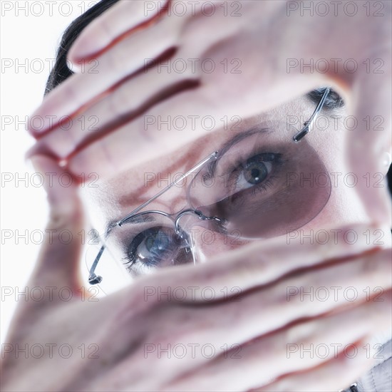 Portrait of young woman making finger frame over glasses.