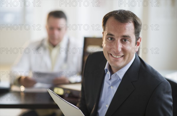 USA, New Jersey, Jersey City, Portrait of male patient holding medical results in office.