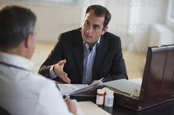 USA, New Jersey, Jersey City, Medical sales representative talking with doctor in office.