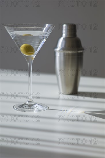 Cocktail shaker and cocktail in glass.