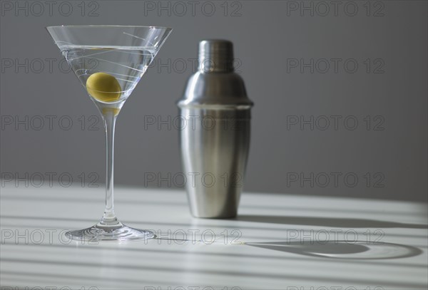 Cocktail shaker and cocktail in glass.