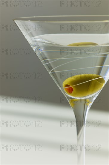 Cocktail with olive in glass.